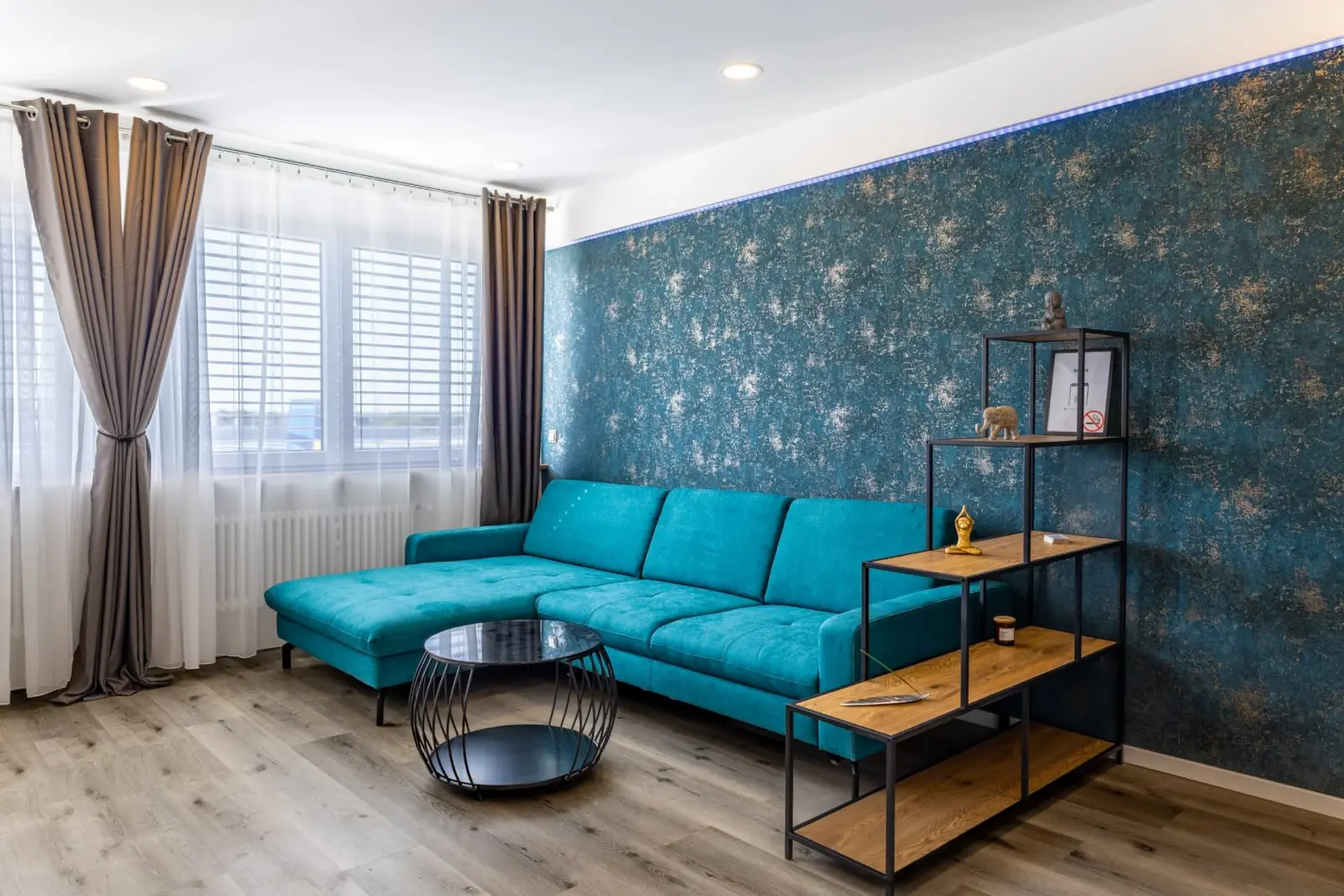 Modernes Wohnzimmer mit türkisfarbenem Sofa in den M4 Apartments Freiburg